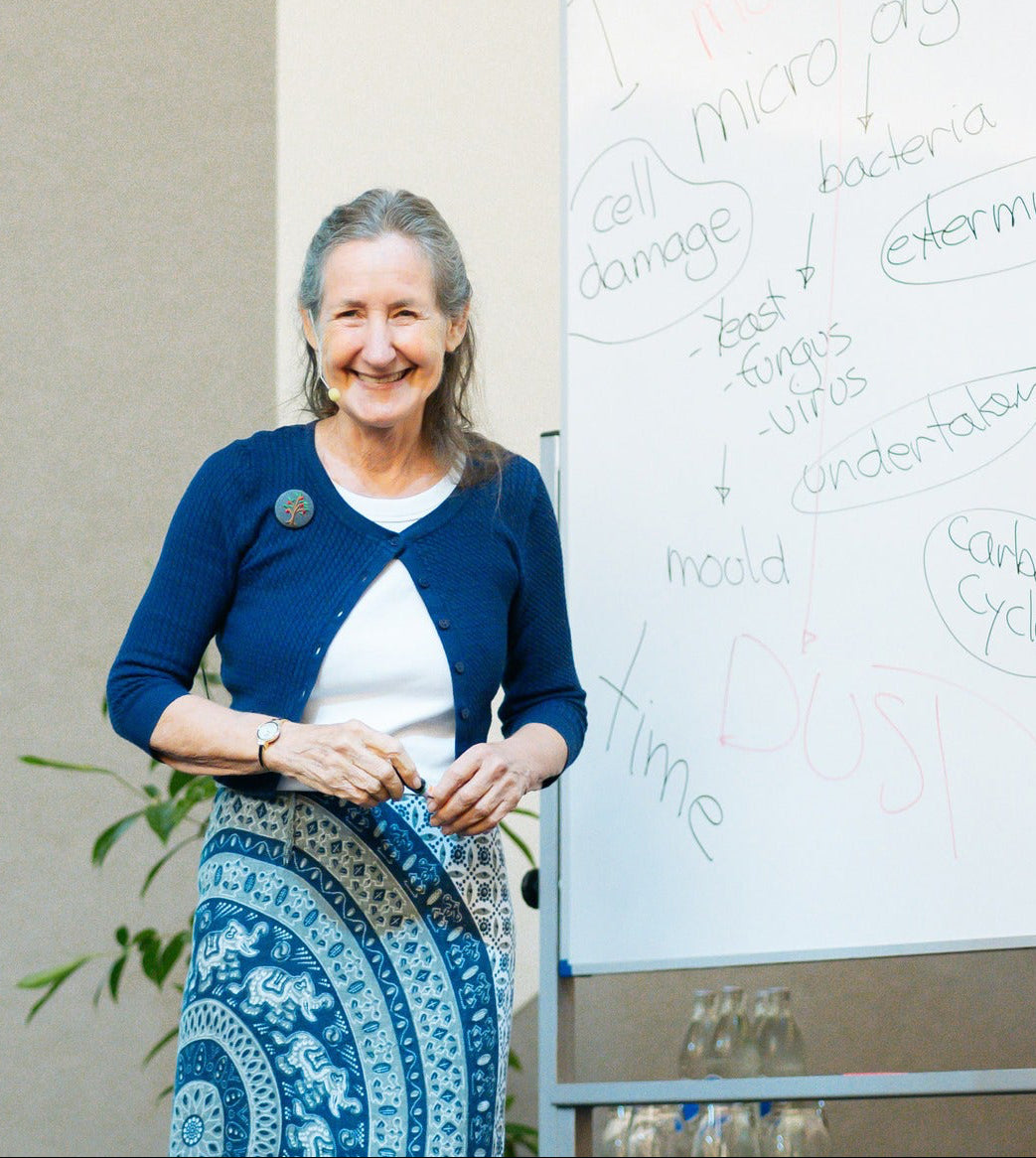 Barbara o'neill standing in front of a whiteboard with notes, smiling. teaching a class at the top health conference in the United States 